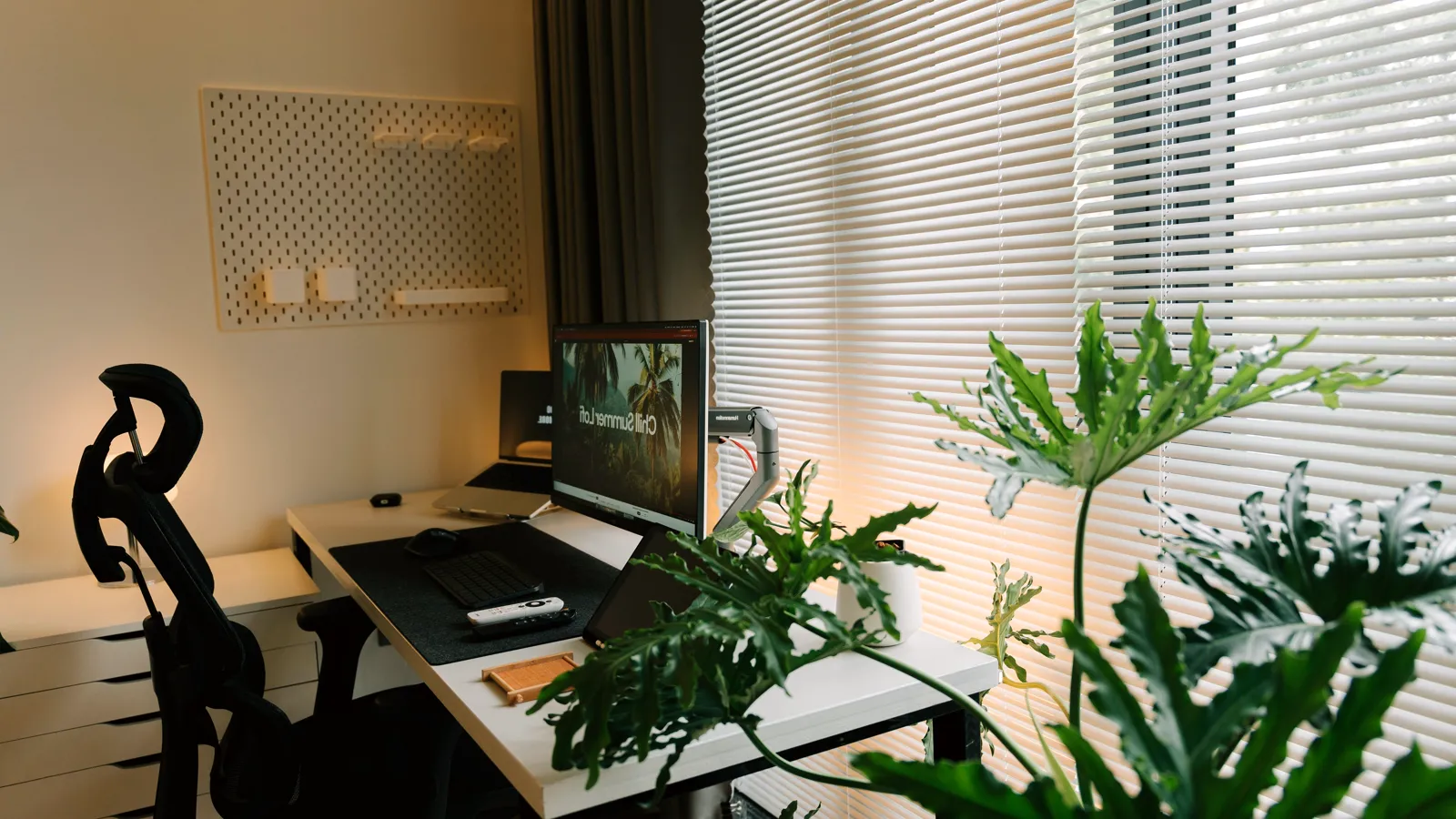 Home office desk by a window with a monitor arm and an ergonomic chair